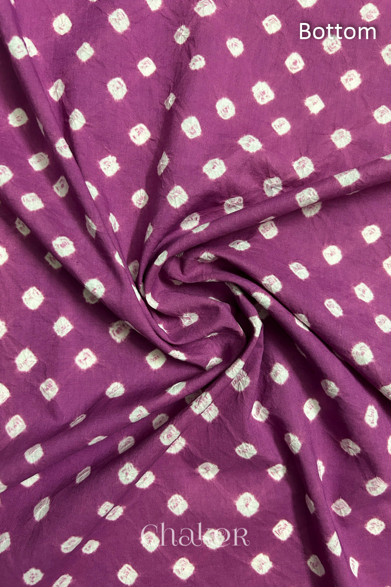 Close-up of violet puprle fabric featuring bandhani pattern of white dots, arranged in a swirly style showcasing the textile's texture and design details.Text reads bottom details.

