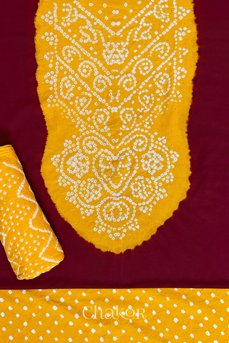 A classic red set fabric featuring sparkly mukaish embroidered contrast yellow yoke & bottom and dupatta rolled beautifully and placed on the fabric. Text reads Chakor.
