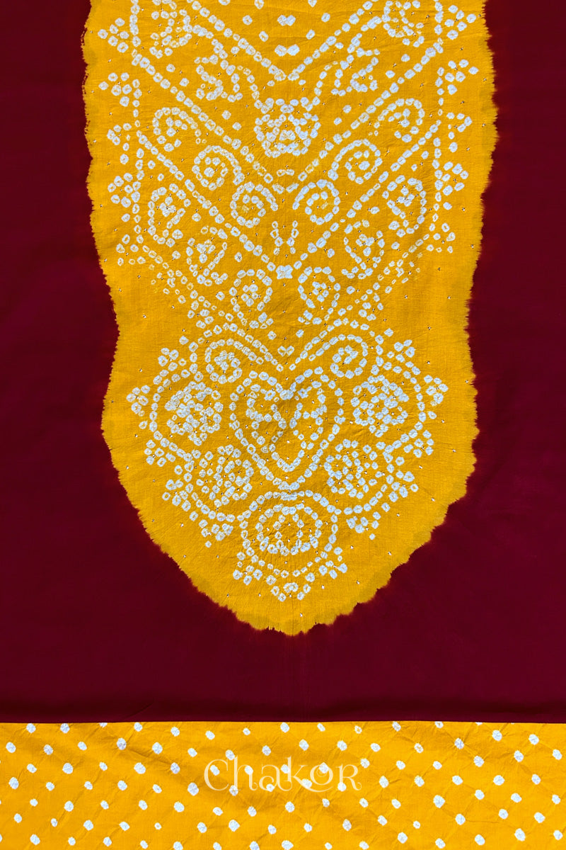Close-up of red kurta fabric featuring intricate bandhani & yellow mukaish embroidered yoke with bandhani dotted bottom fabric, with Chakor brand watermark.
