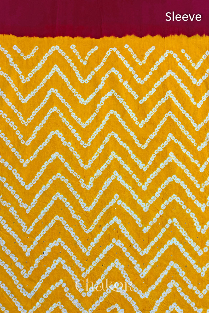 Close-up of yellow bandhani fabric featuring chevron tie-dye design, with Chakor brand watermark. Text reads sleeve.
