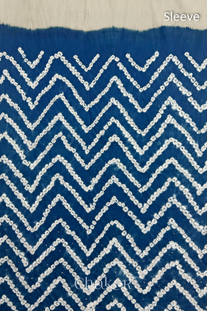 Close-up of  indigo blue bandhani fabric featuring chevron tie-dye design, with Chakor brand watermark. Text reads sleeve.
