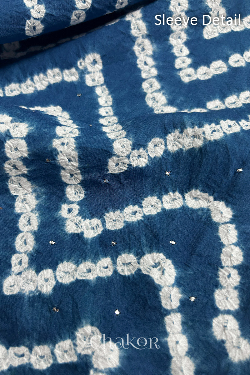 Close-up of  indigo blue bandhani fabric featuring chevron tie-dye design, showcasing sparkly mukaish embroidery with Chakor brand watermark. Text reads sleeve details.
