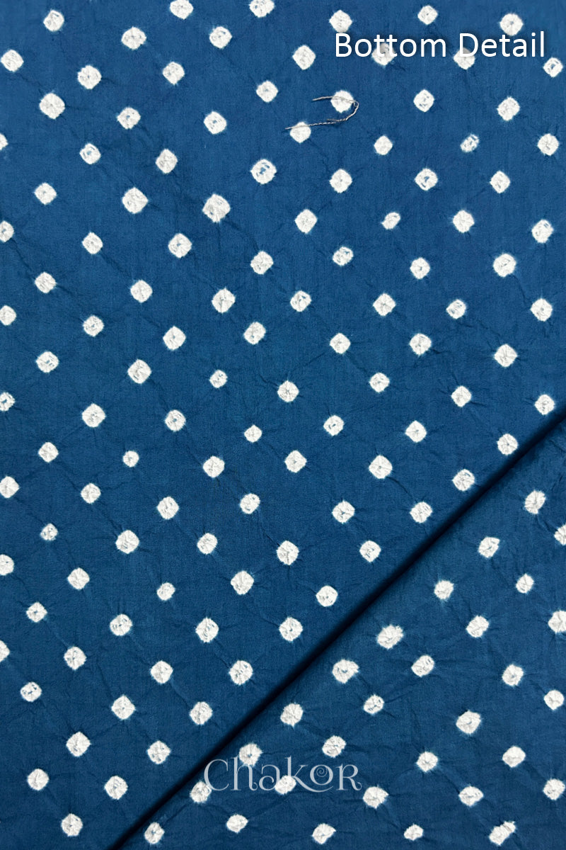 Close up of bottom fabric in indigo blue patterned with bandhani tie dye dots, folded at the corner displaying texture and detail. Text reads bottom.
