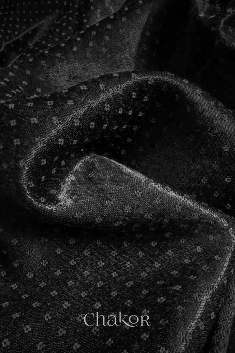 Close-up of black mashru self textured fabric with 'Chakor' logo visible.