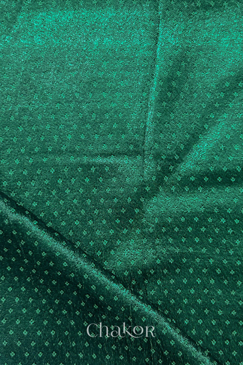 Dark green mashru self textured fabric with folded corner & Chakor brand watermark.
