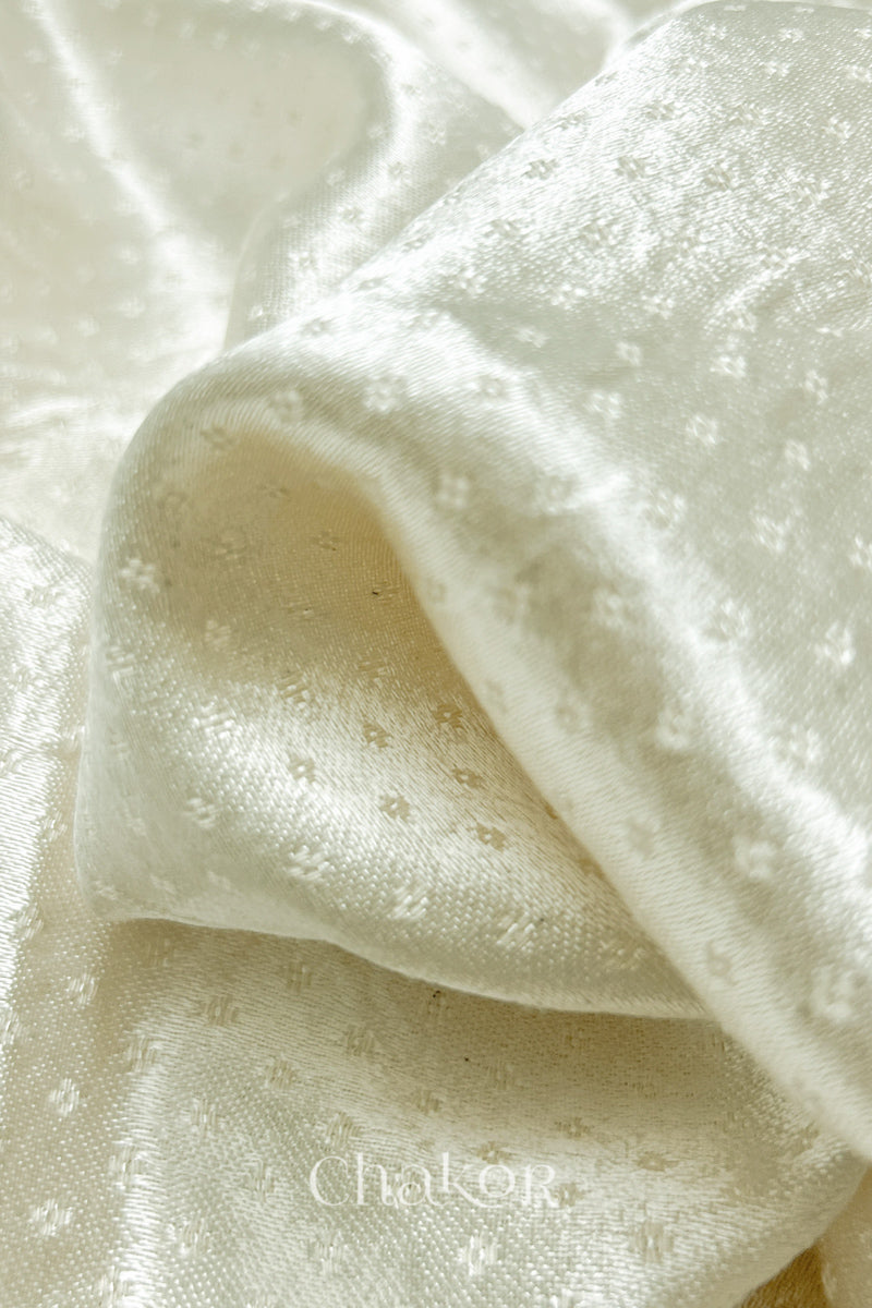 Close-up of off-white mashru self textured fabric with 'Chakor' logo visible.