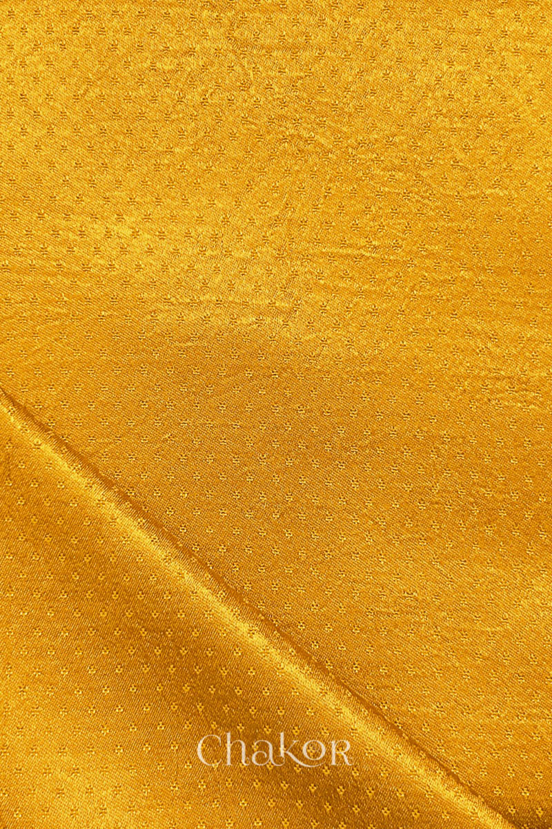 Golden yellow Mashru fabric folded edge detail with subtle sheen.
