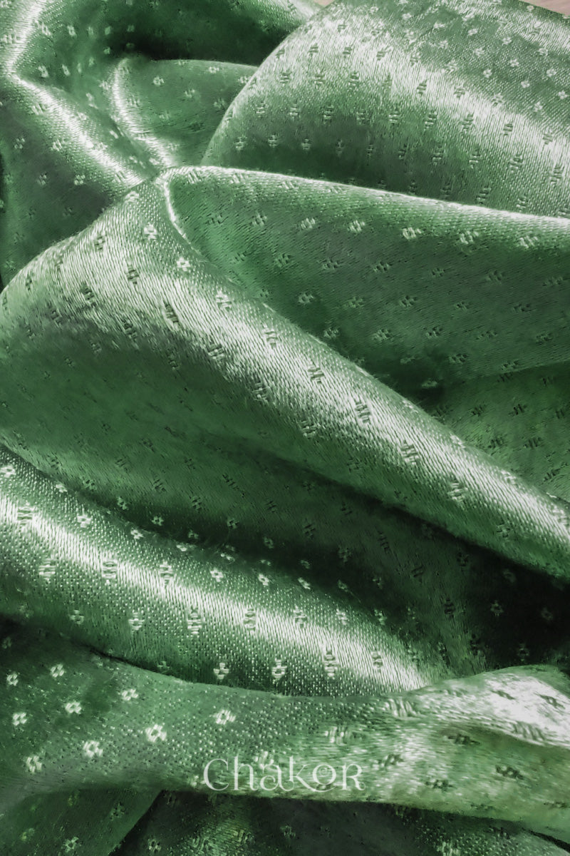 Close-up of pista green mashru self textured fabric with 'Chakor' logo visible.