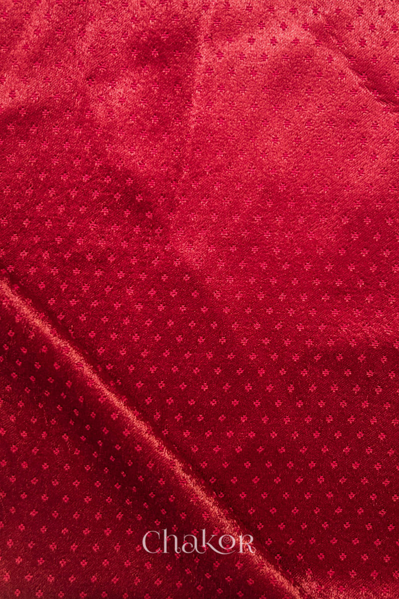 Flat lay red mashru silk fabric with a self woven subtle pattern, featuring the brand 'Chakor'.
