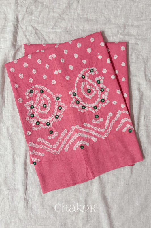 Pink Kutch Bandhani cotton unstitched blouse fabric with Keri pattern piece folded on white fabric.

