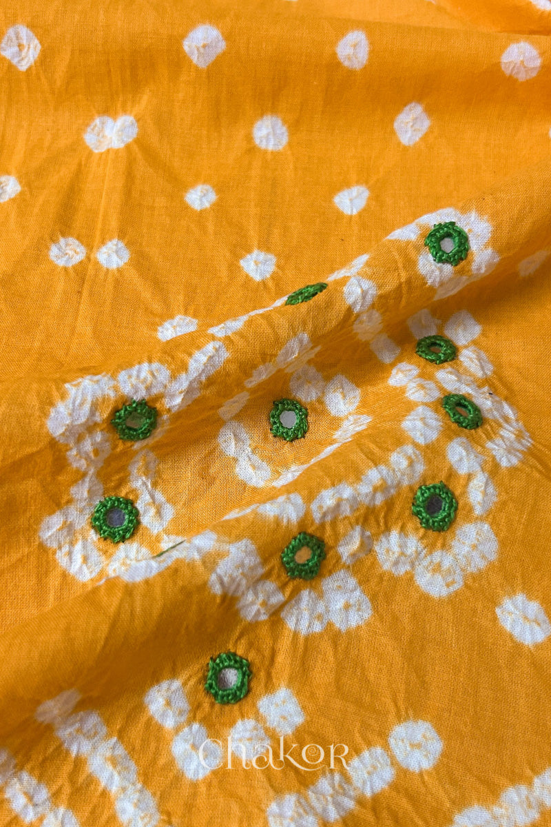 Detail of Kutch Bandhani Keri pattern with mirror embroidery on yellow cotton blouse fabric.
