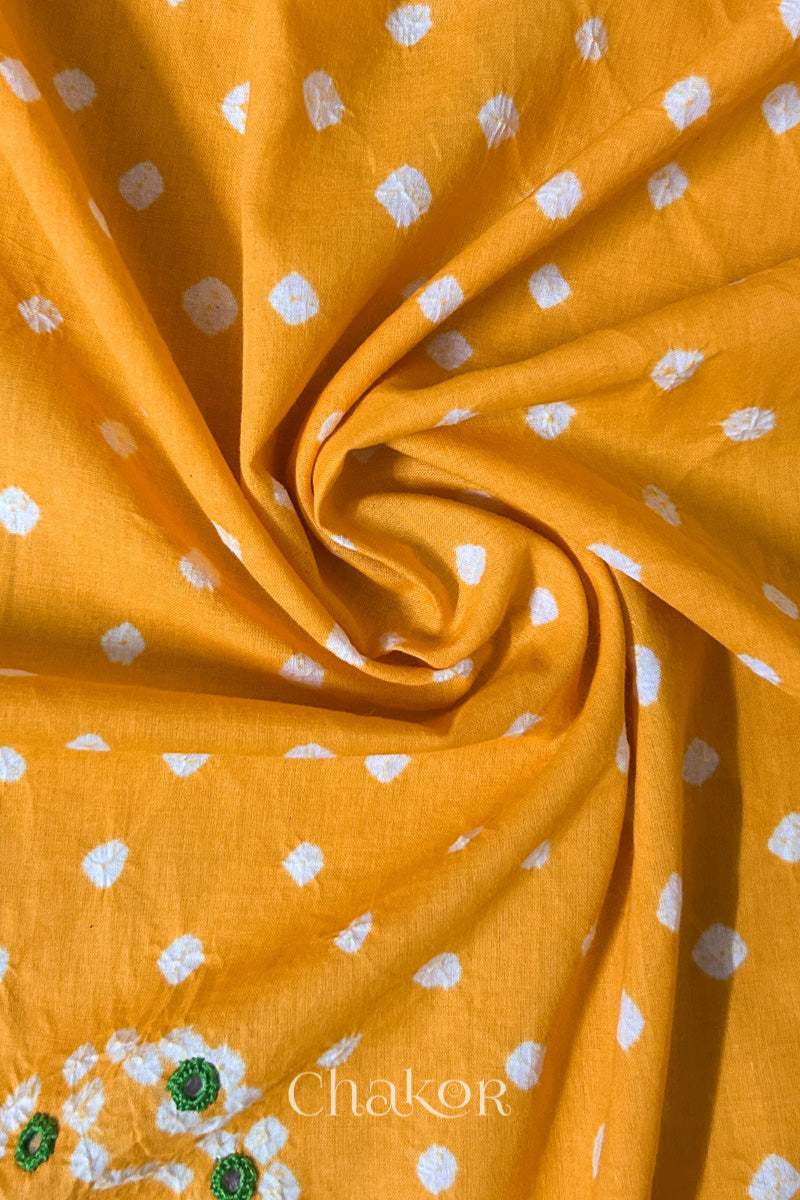 Yellow Bandhani cotton blouse fabric showing fine tie-dye dots and its soft drape.
