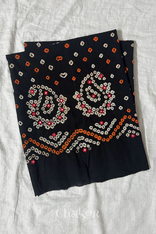 Black Kutch Bandhani cotton unstitched blouse fabric with Keri pattern piece folded on white fabric.
