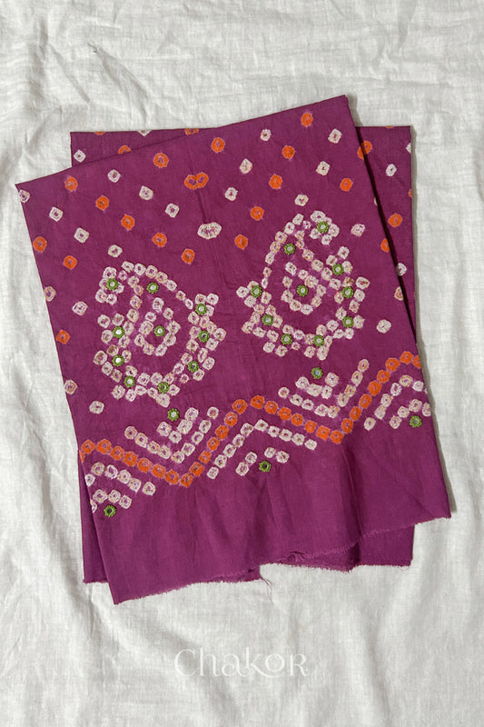Magenta Kutch Bandhani cotton unstitched blouse fabric with Keri pattern piece folded on white fabric.
