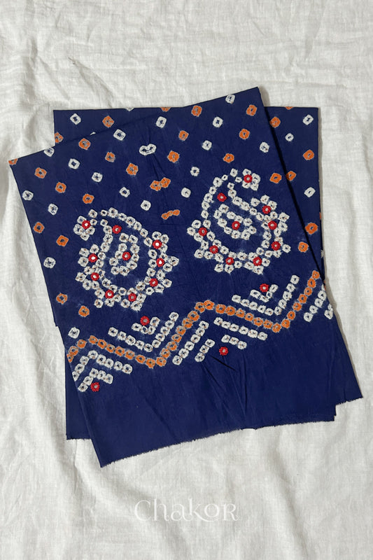 Navy Kutch Bandhani cotton unstitched blouse fabric with Keri pattern piece folded on white fabric.

