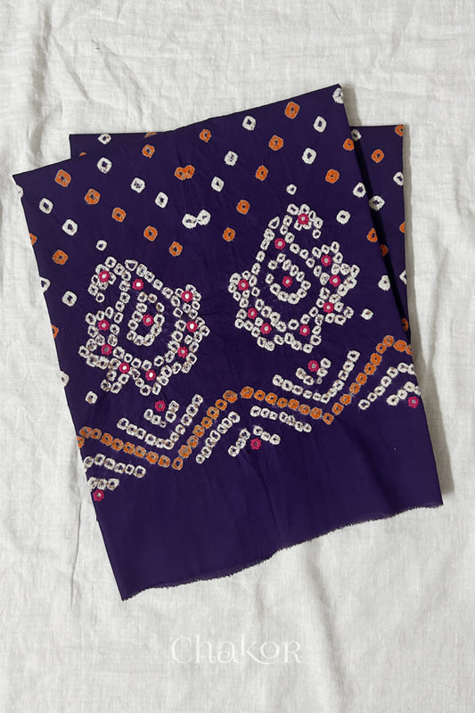 Purple Kutch Bandhani cotton unstitched blouse fabric with Keri pattern piece folded on white fabric.

