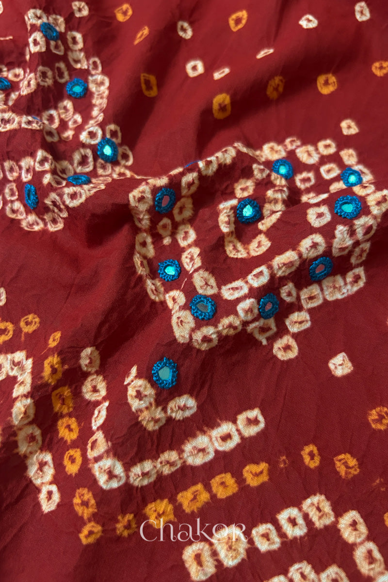 Close-up of Red Kutch Bandhani blouse fabric showing Keri motifs and hand-embroidered mirror work.
