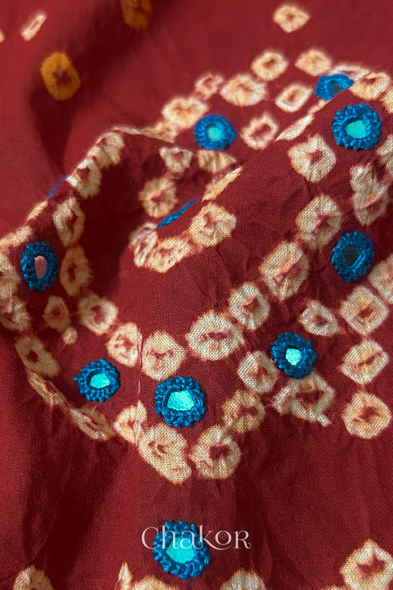 Detail of Kutch Bandhani Keri pattern with mirror embroidery on Red cotton blouse fabric.
