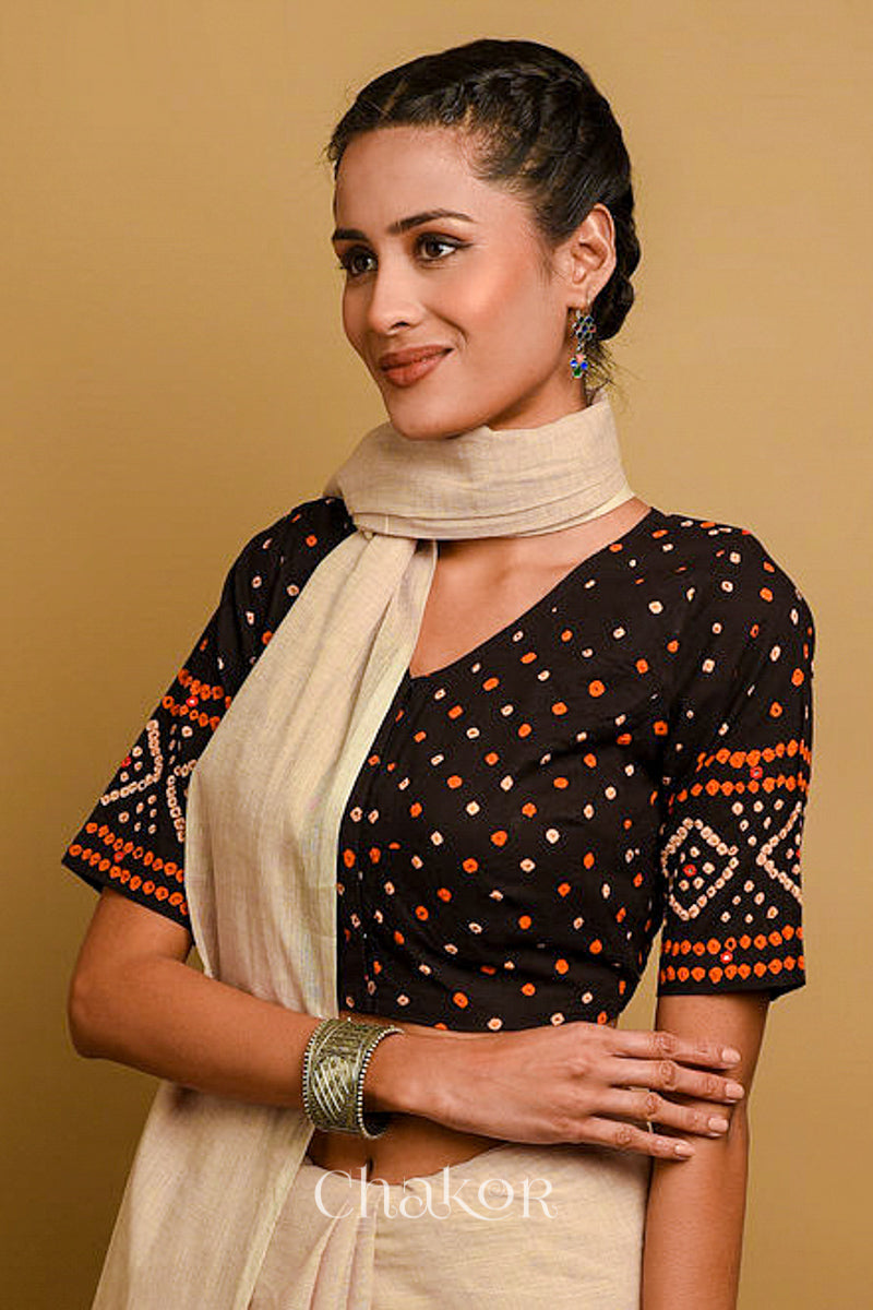 Woman wearing a handcrafted black bandhani cotton blouse in traditional patterns with mirror embroidery.