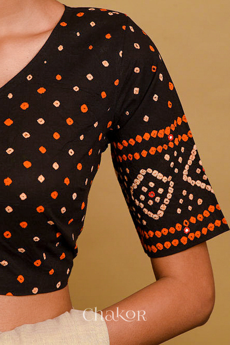 Woman wearing a handcrafted black bandhani cotton blouse in traditional patterns with mirror embroidery.