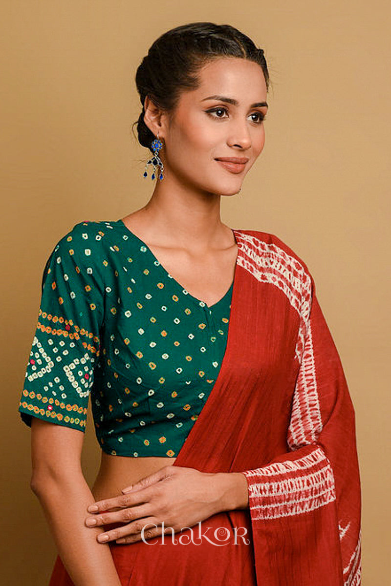 Woman wearing a handcrafted green bandhani cotton blouse in traditional patterns with mirror embroidery.