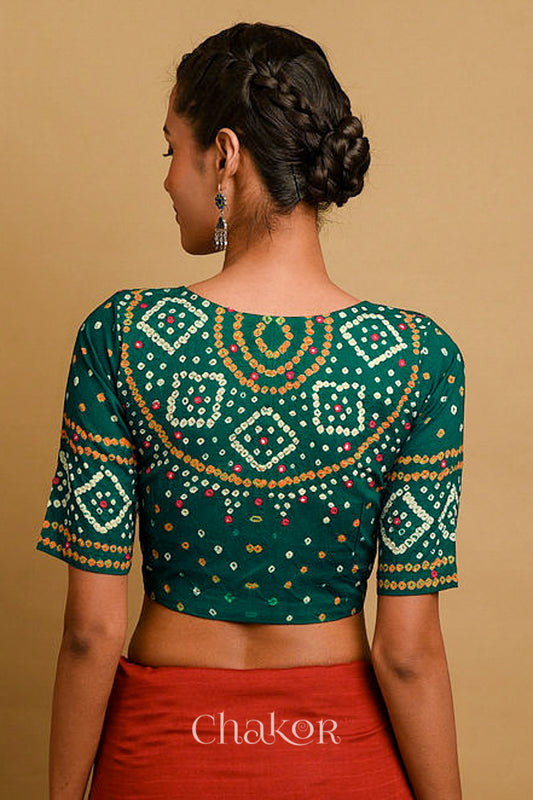Woman wearing a handcrafted green bandhani cotton blouse in traditional patterns with mirror embroidery.