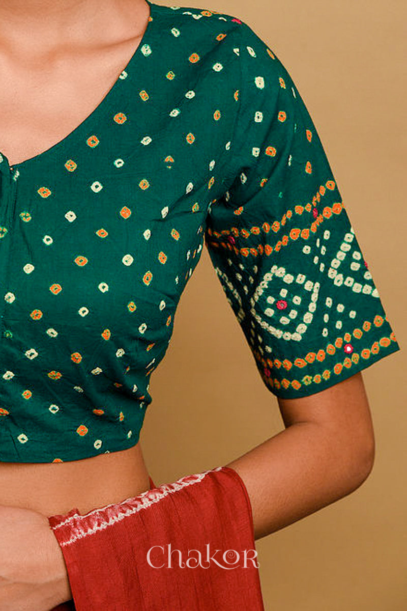 Woman wearing a handcrafted green bandhani cotton blouse in traditional patterns with mirror embroidery.