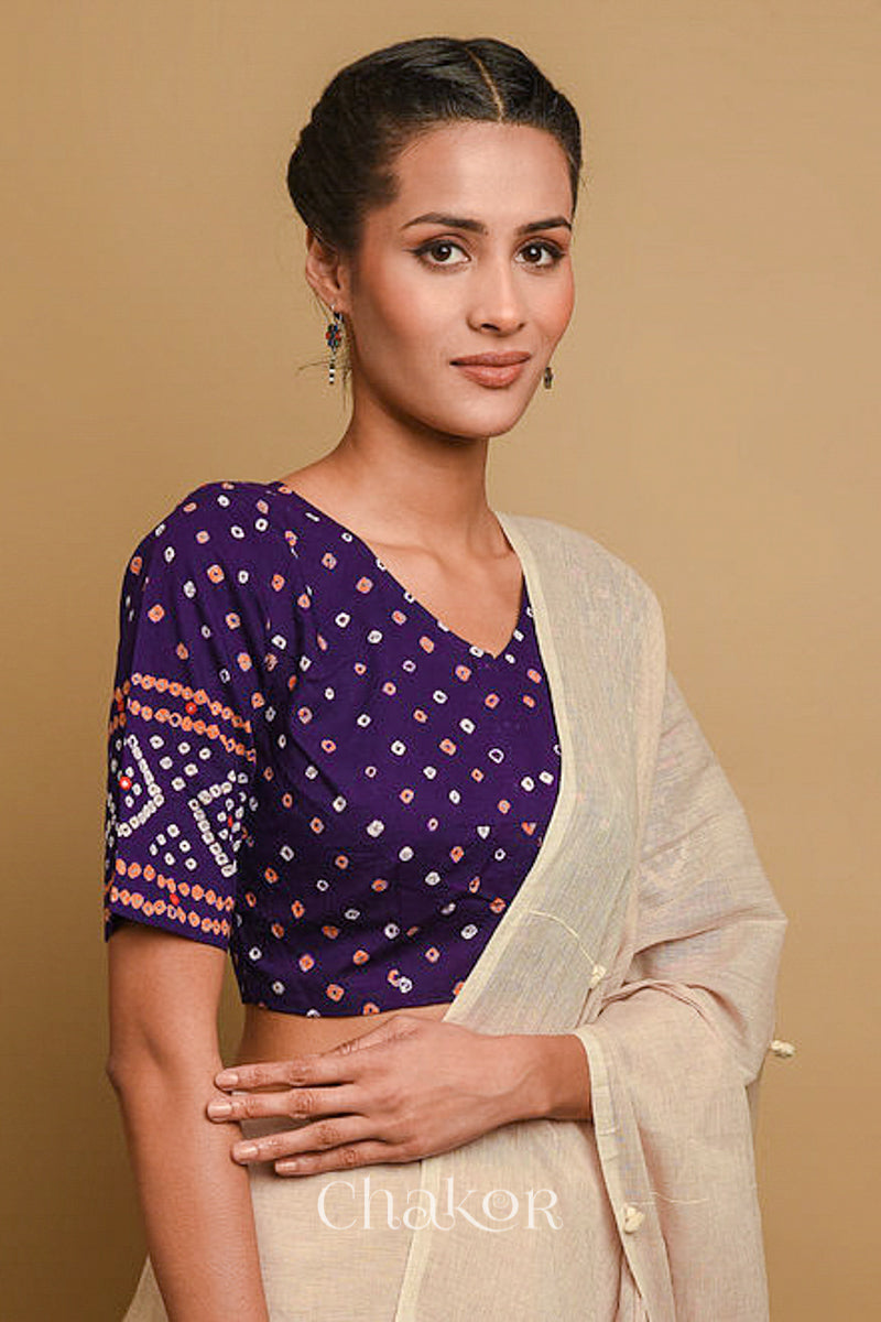 Woman wearing a handcrafted purple bandhani cotton blouse in traditional patterns with mirror embroidery.