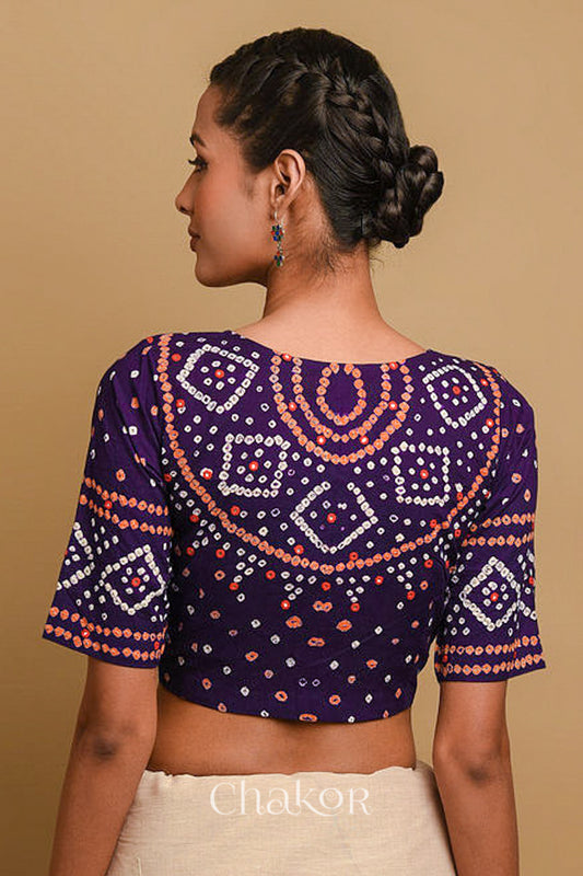Woman wearing a handcrafted purple bandhani cotton blouse in traditional patterns with mirror embroidery.