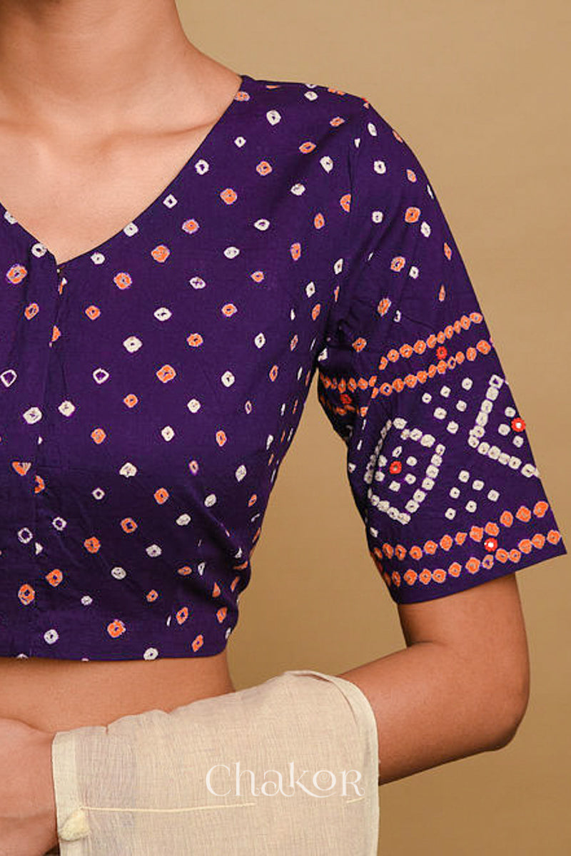 Woman wearing a handcrafted purple bandhani cotton blouse in traditional patterns with mirror embroidery.