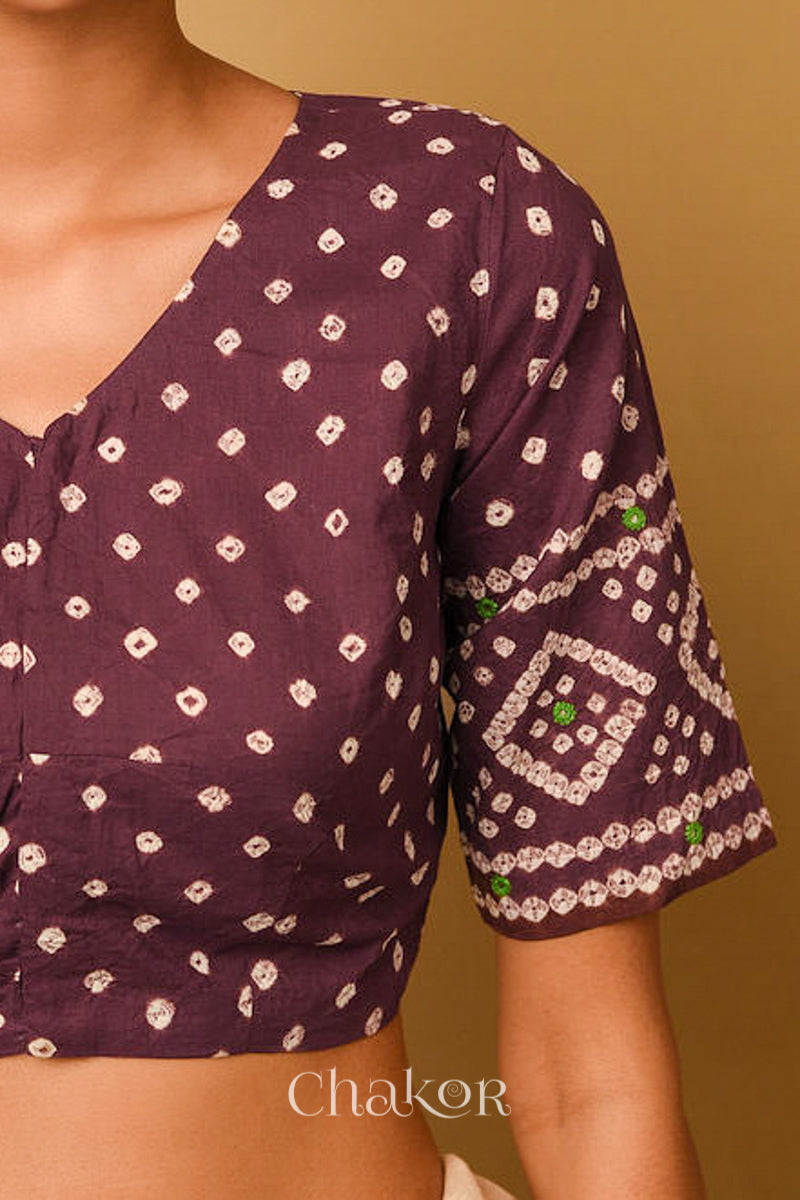 Woman wearing a handcrafted brown bandhani cotton blouse in traditional patterns with mirror embroidery.