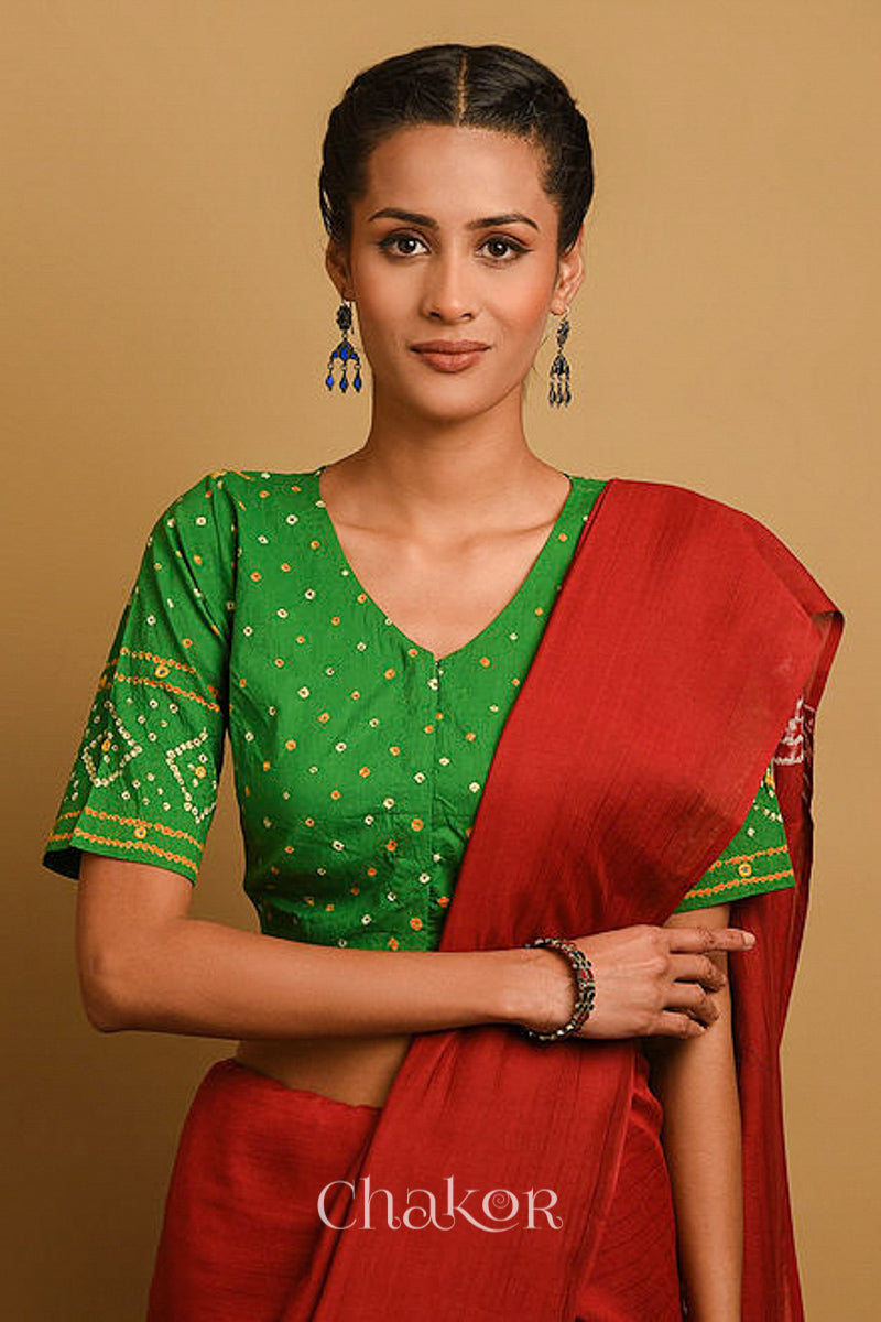 Woman wearing a handcrafted green bandhani blouse in traditional patterns with mirror embroidery.