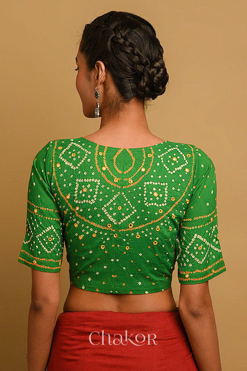 Woman wearing a handcrafted green bandhani blouse in traditional patterns with mirror embroidery.