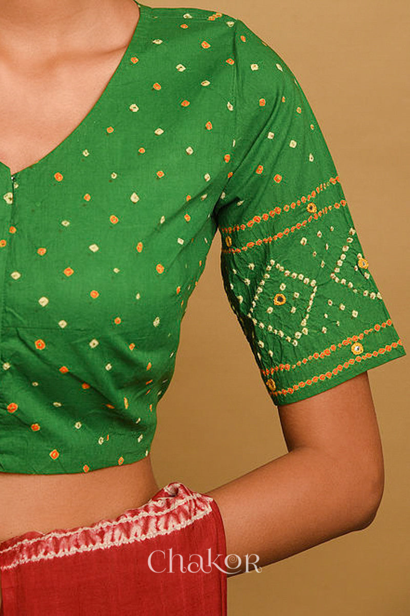Woman wearing a handcrafted green bandhani blouse in traditional patterns with mirror embroidery.