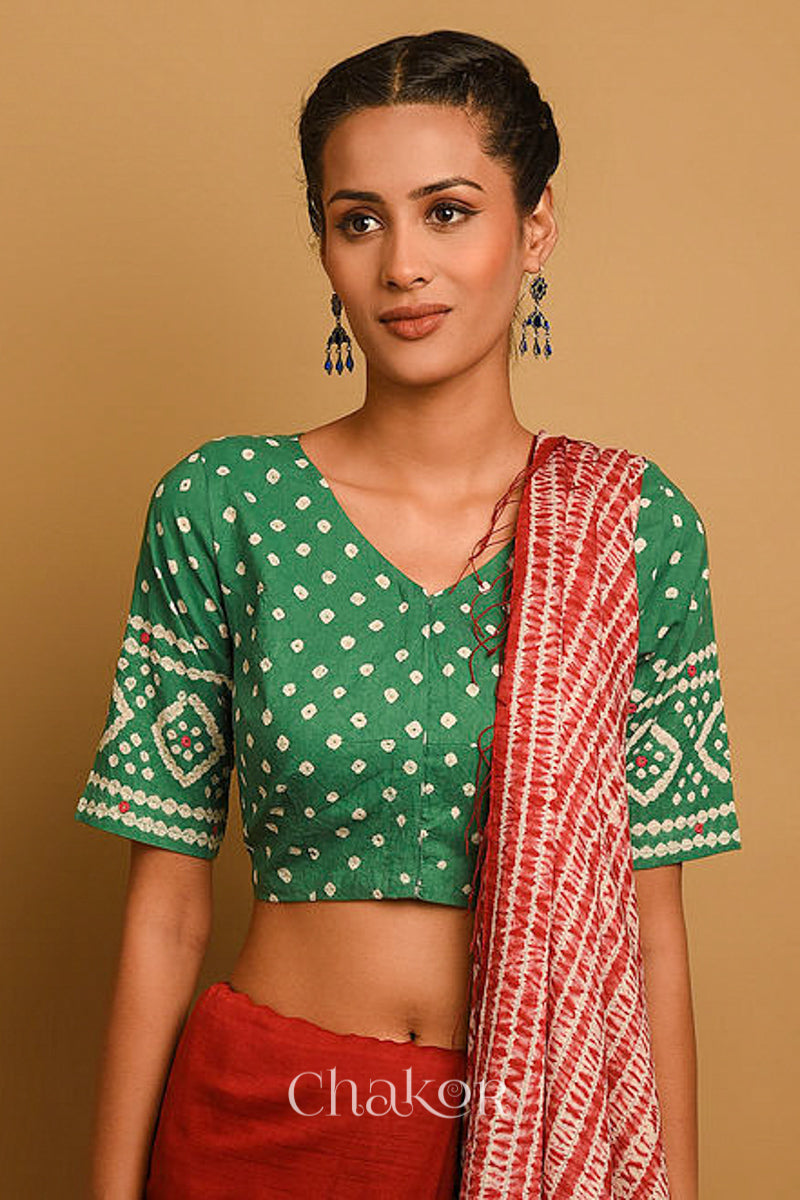 Woman wearing a handcrafted moss green bandhani blouse in traditional patterns with mirror embroidery.