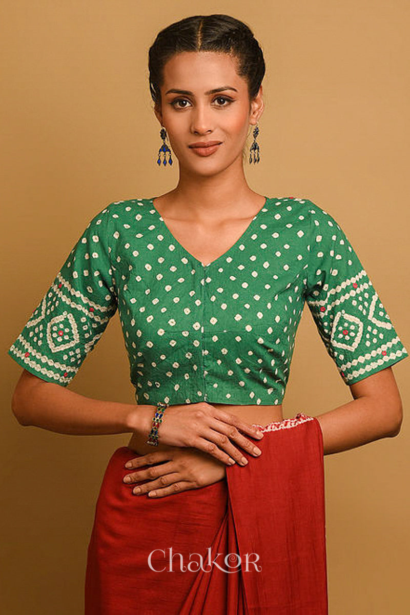 Woman wearing a handcrafted moss green bandhani blouse in traditional patterns with mirror embroidery.