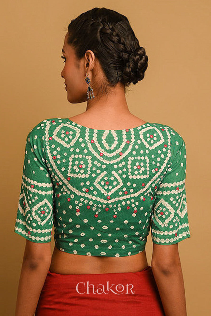Woman wearing a handcrafted moss green bandhani blouse in traditional patterns with mirror embroidery.