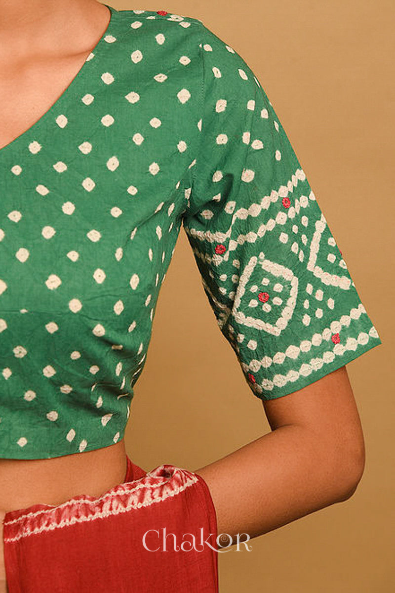 Woman wearing a handcrafted moss green bandhani blouse in traditional patterns with mirror embroidery.