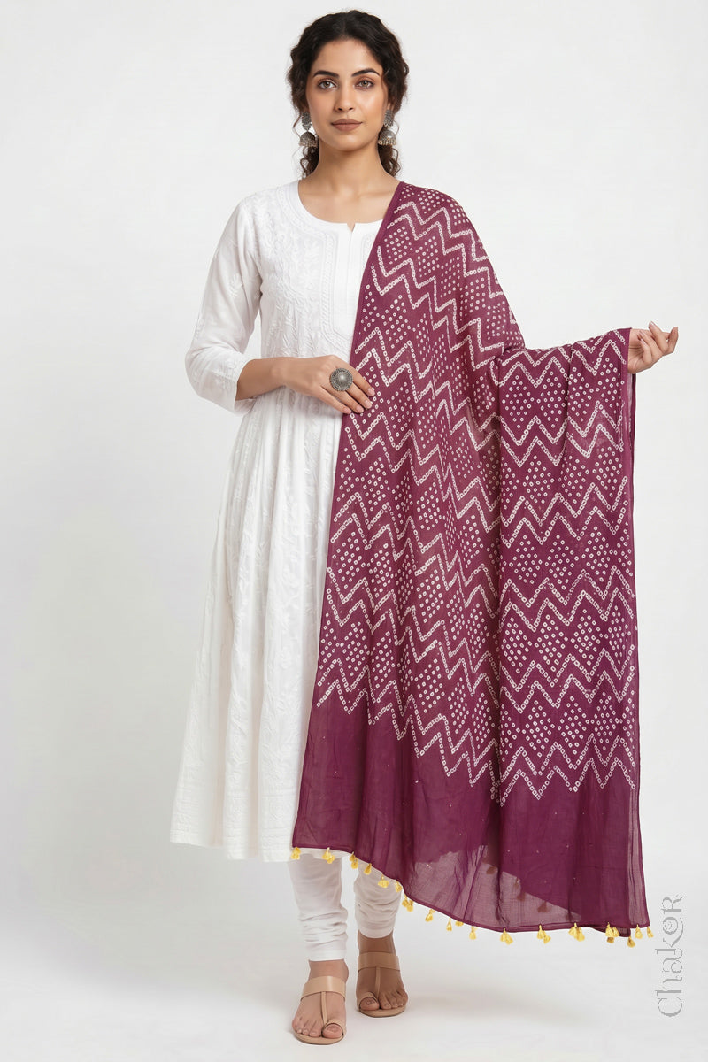 Plum pink Kutch Bandhani mulmul dupatta wrapped around woman's neck.
