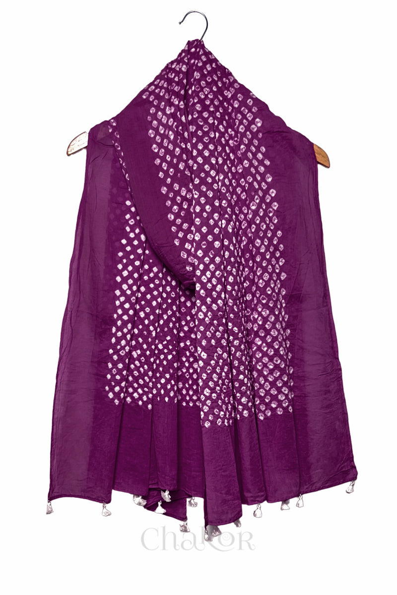 Magenta Bandhani mul cotton dupatta draped on hanger showing tie-dye dot pattern and tasselled edge.

