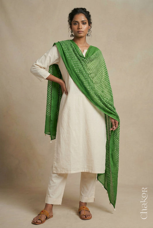 Model wearing mehendi Bandhani mul cotton dupatta with tie-dye dot pattern and pallu edged with tassels draped over a white kurta.