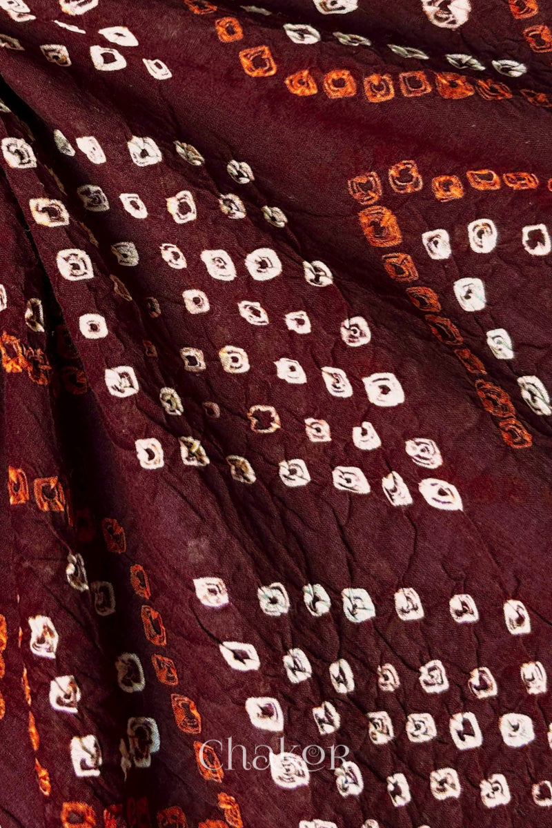 Close-up of hand tied Bandhani dots on maroon mulmul cotton fabric.
