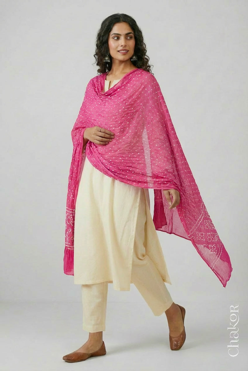Model wearing pink Bandhani mul cotton dupatta with tie-dye dot pattern paired with a white kurta.