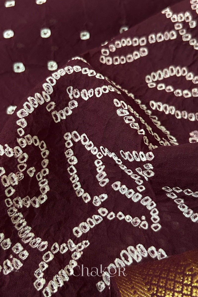 Close-up of white pearl-like dots in the maroon Kutch Bandhani tie-dye pattern.
