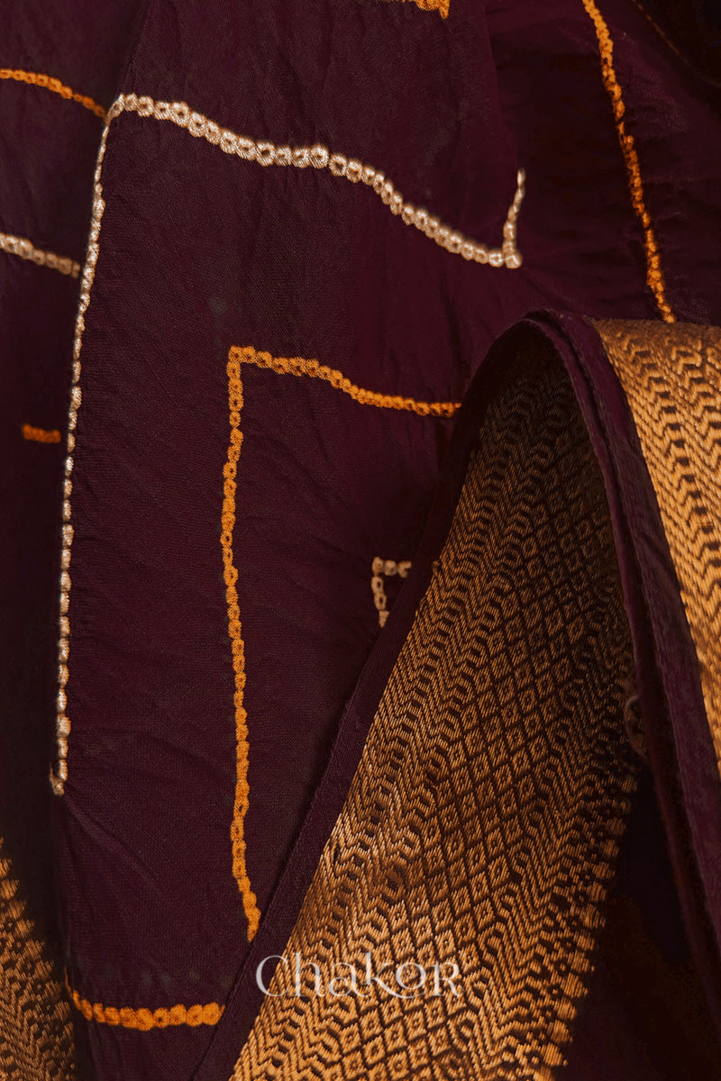 Close-up of Maroon sarees featuring rai bandhani and zari weaving showcasing beautiful craftsmanship.
