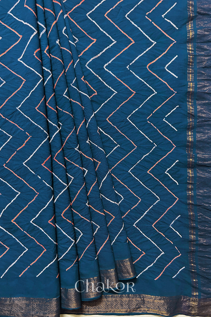 Indigo Blue saree, neatly arranged in pleats with Rai Bandhej zigzag pattern and 'Chakor' brand watermark.