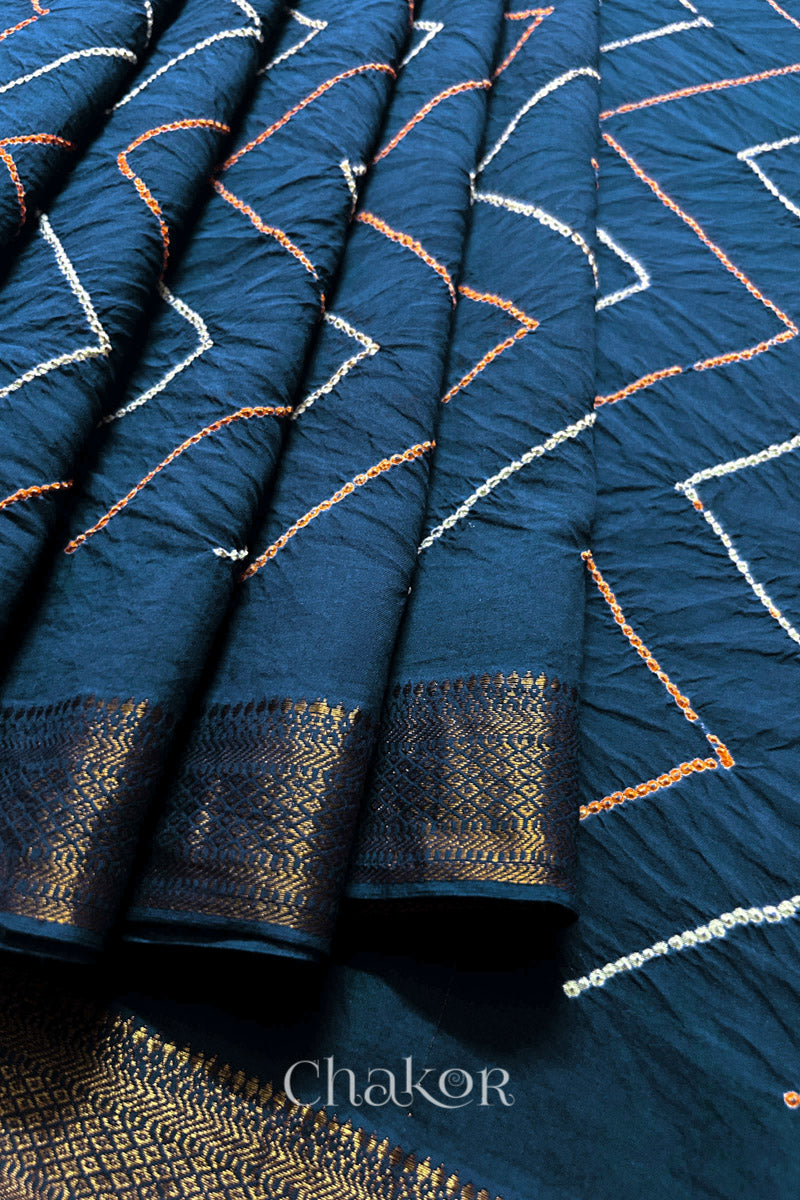 Close-up of indigo blue saree pleats with rai bandhani and zari weaving showcasing beautiful craftsmanship.

