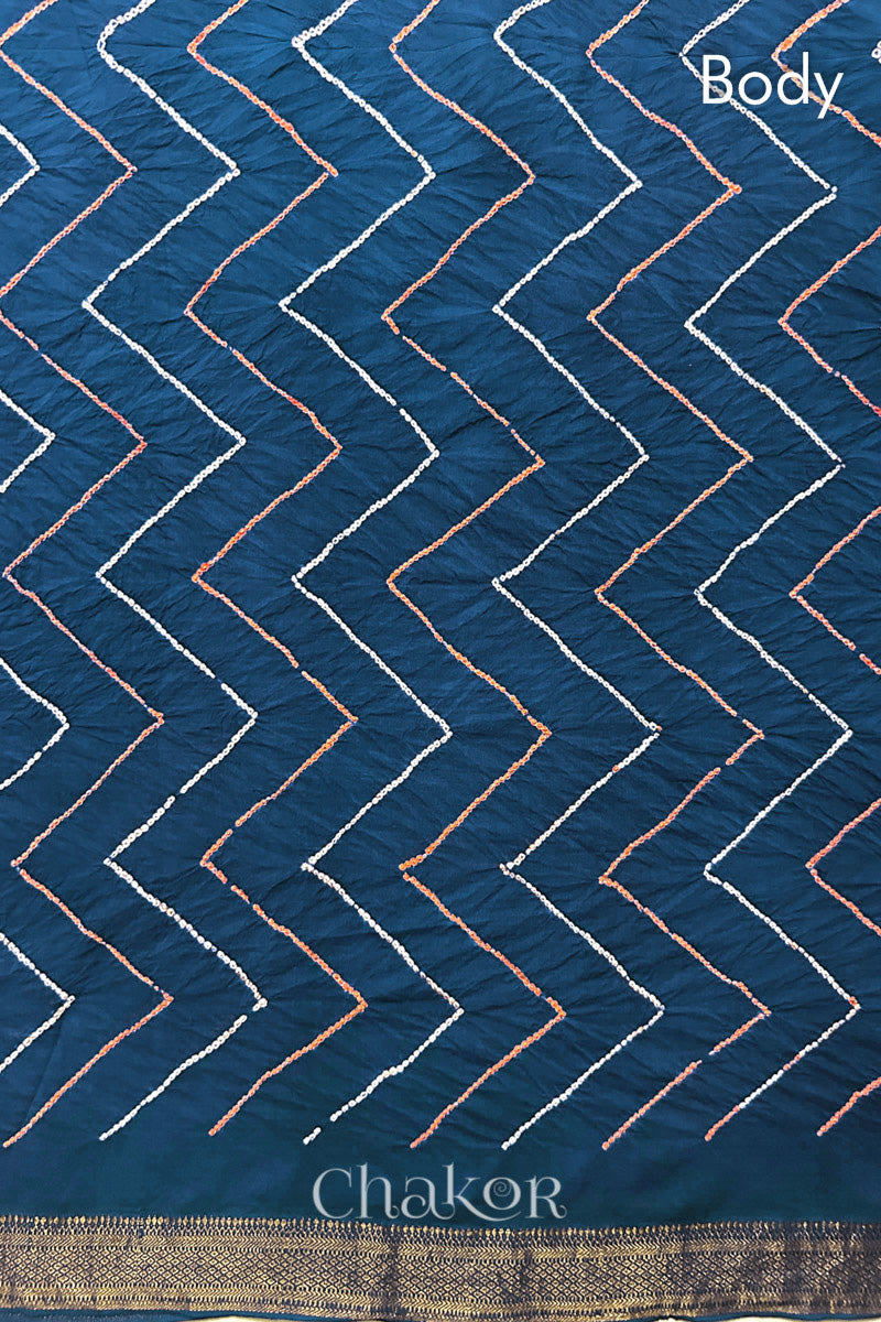Body detail of indigo blue bandhani saree with woven golden zari border. Watermark text reads 'Chakor'.
