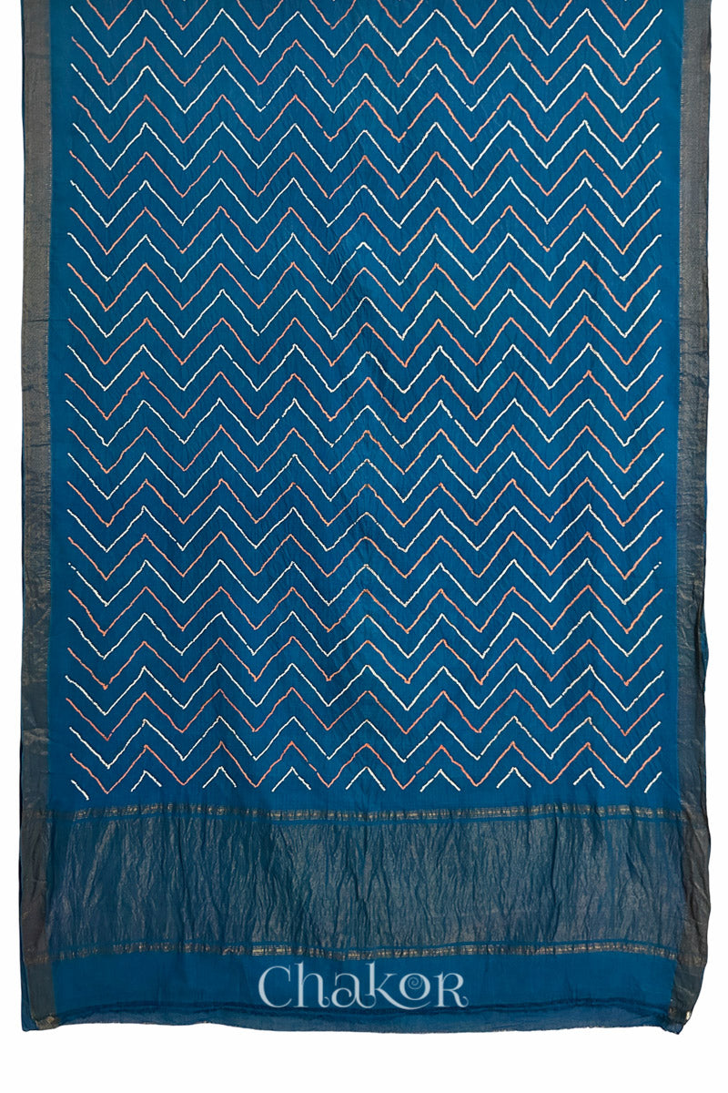 Indigo Blue saree, flat draped with Rai Bandhej zigzag pattern against white background and 'Chakor' brand watermark.
