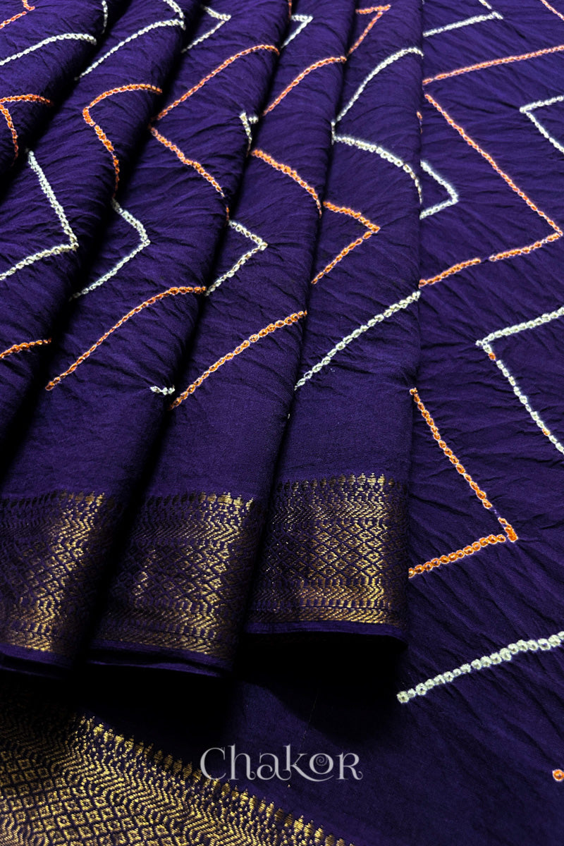 Close-up of Purple saree pleats with rai bandhani and zari weaving showcasing beautiful craftsmanship.
